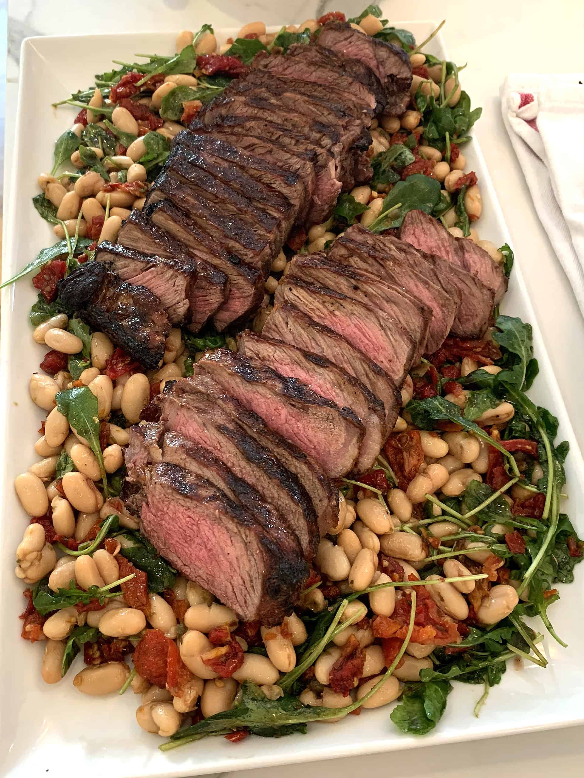 Roasted beef tenderloin over white beans, arugula, and sun-dried tomatoes with vinaigrette
