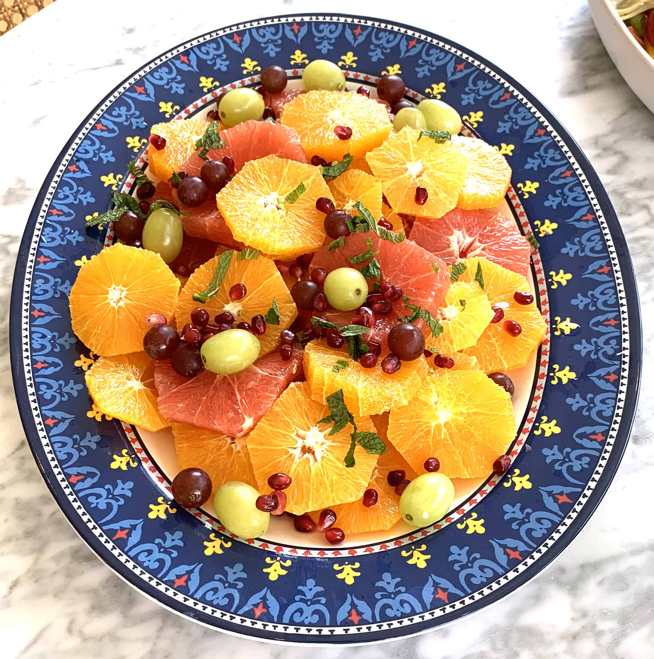 Fruit salad with oranges and grapefruit slices, grapes, and pomegranate with mint