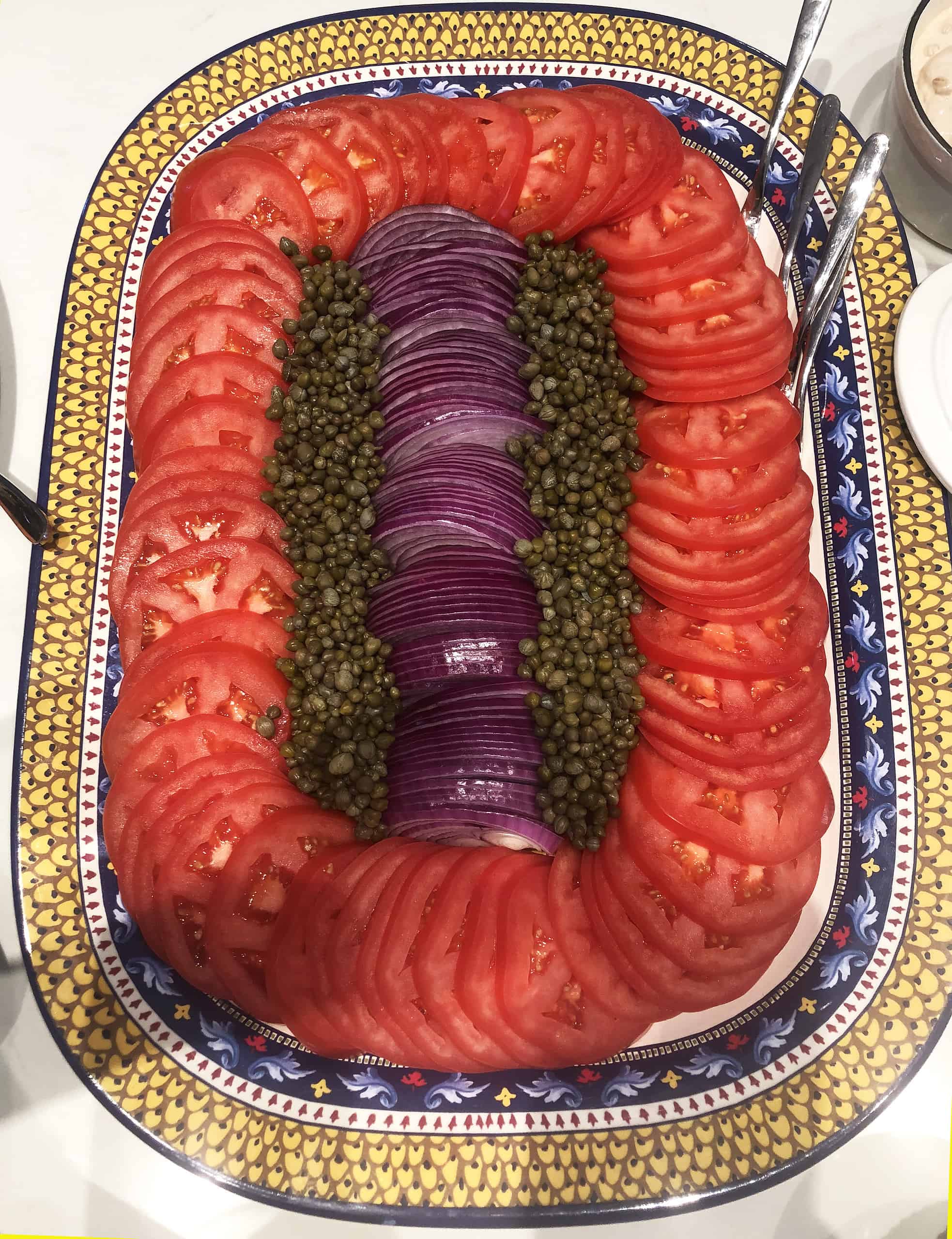 Platter of tomato slices, red onion slice, and capers