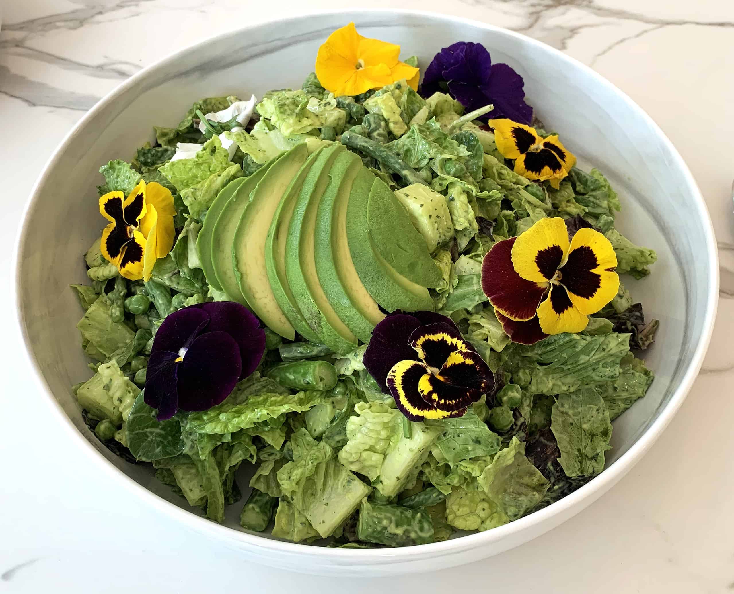Romaine salad with avocado, vinaigrette, and pansies