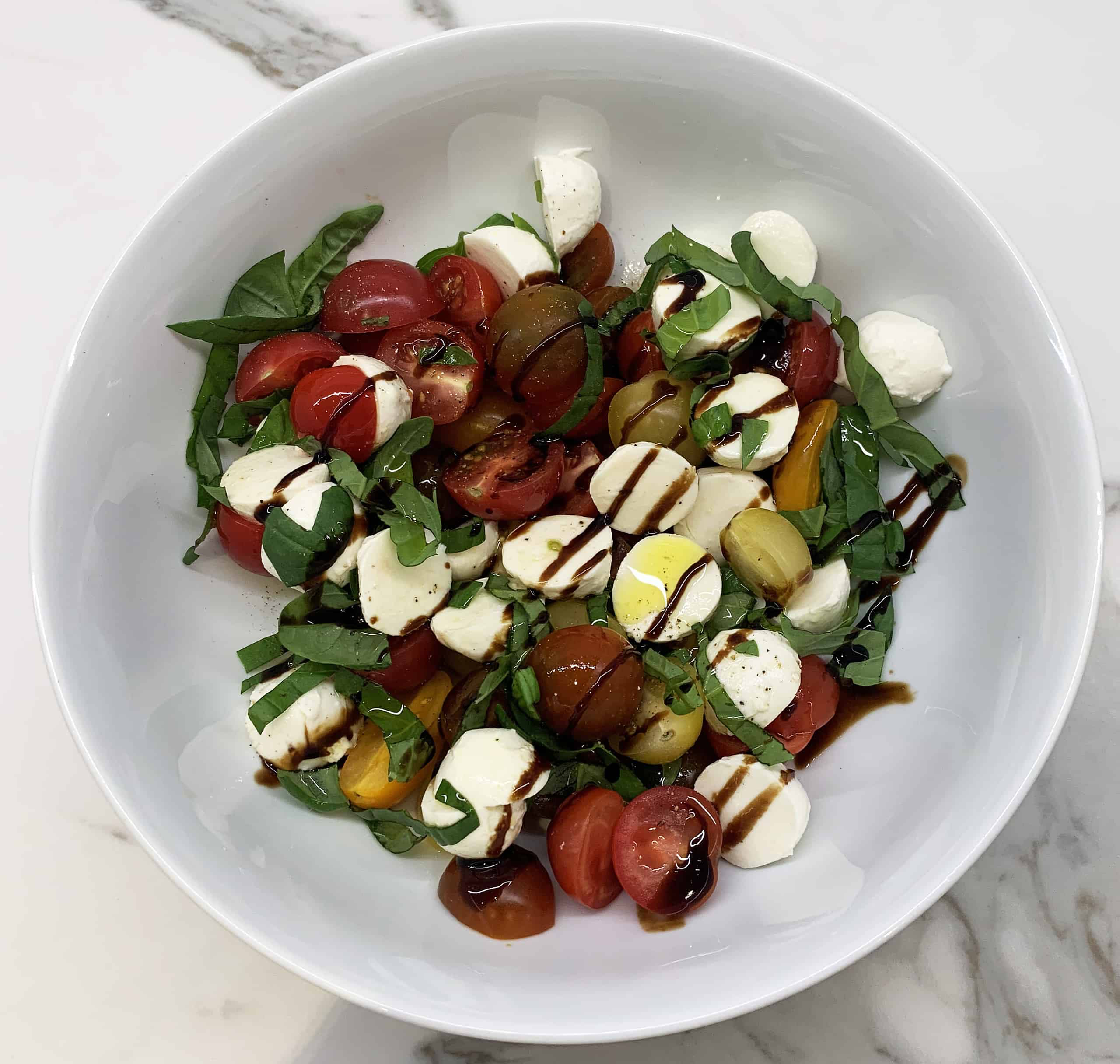 Fresh mozzarella, yellow and red cherry tomatoes, and basil salad with balsamic dressing